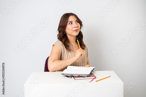Mujer joven buscando inspiración para escribir en escritorio con fondo neutro