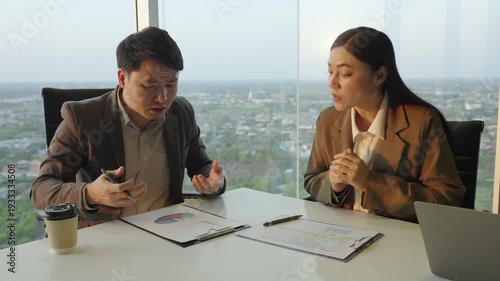 two business partners meeting and looking at documents with stressed and confused expressions in modern office