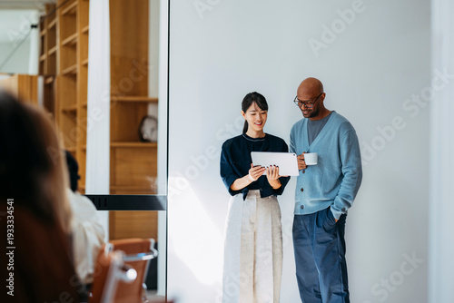 Two Colleagues Collaborate Over Tablet In Office