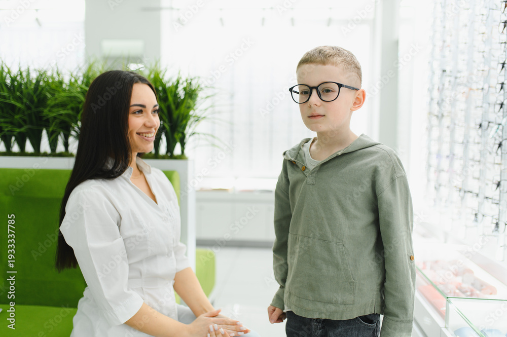 Obraz premium Optometrist helping boy choosing new vision glasses