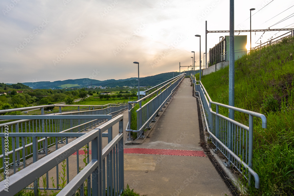 Obraz premium A concrete walkway creating barrier-free access to a small railway station.