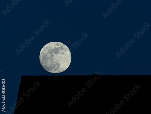 Moon over roof. A nearly full moon over a roof in the evening twilight.

