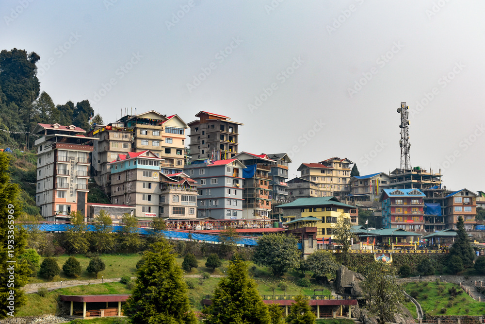 Fototapeta premium Colorful hillside town with multi-story buildings and scenic mountain surroundings in Sikkim. 