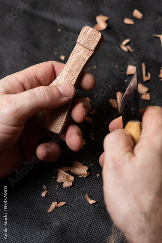 A craftsman cuts a recess into a wooden piece using a chisel