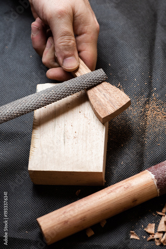 The craftsman gives the desired shape to a wooden blank with a round file