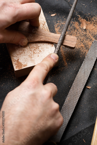 A craftsman sharpens a wooden workpiece with a round file
