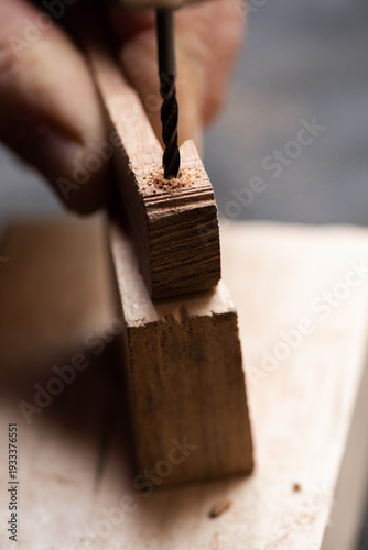 The craftsman drills holes in a wooden workpiece