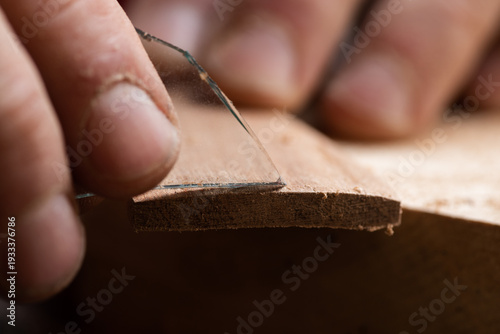 The craftsman sands the surface of a wooden workpiece with a piece of glass