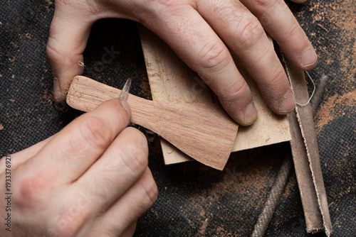 The craftsman scrapes the string holder of the talharpa with a metal scraper