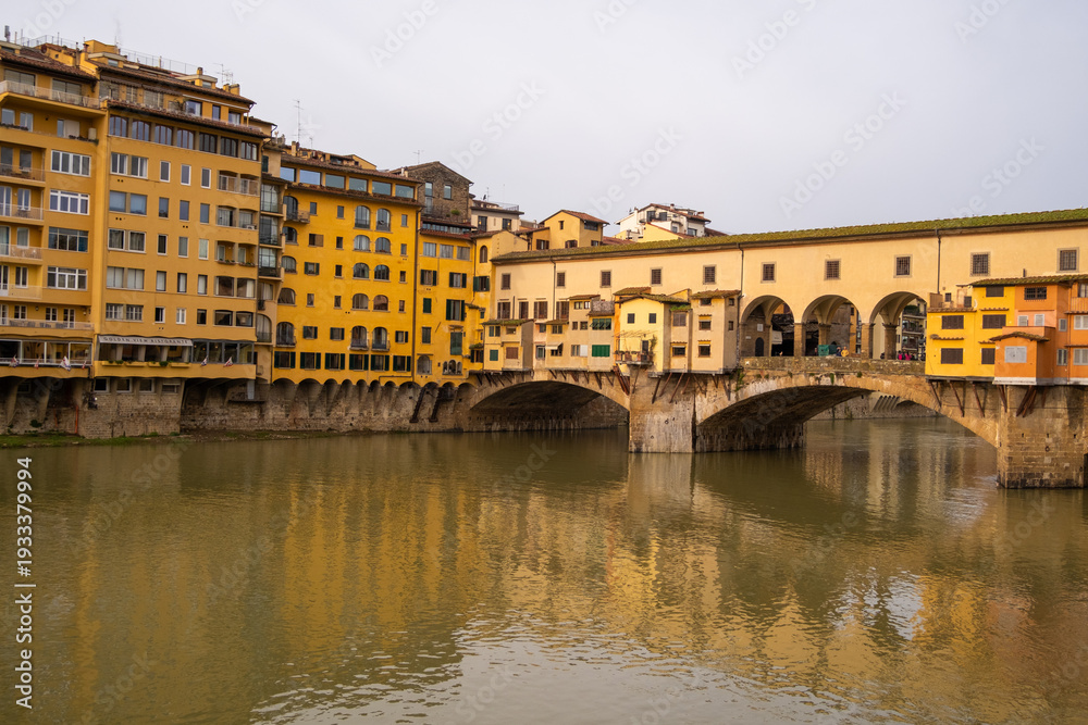 Obraz premium Florence features buildings beside the Arno River with the Ponte Vecchio bridge connecting both sides