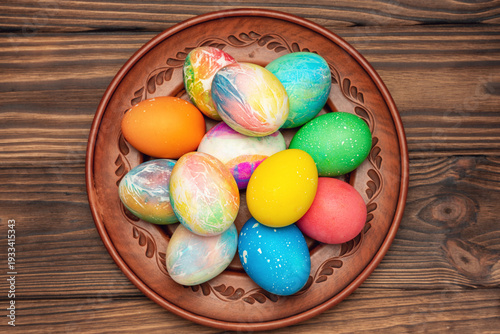 Beautiful tie-dye Easter eggs on a plate on a wooden table