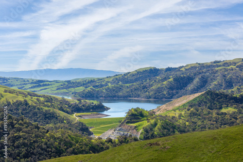 Serene landscape of rolling green east bay hills surrounding a calm San Antonio Reservoir. Sunol Wilderness, Alameda County, California.