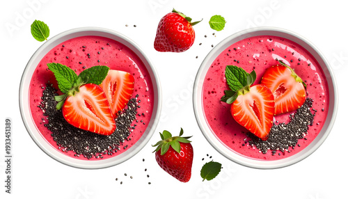 Two pink smoothie bowls with strawberries, mint, and chia seeds on a black background