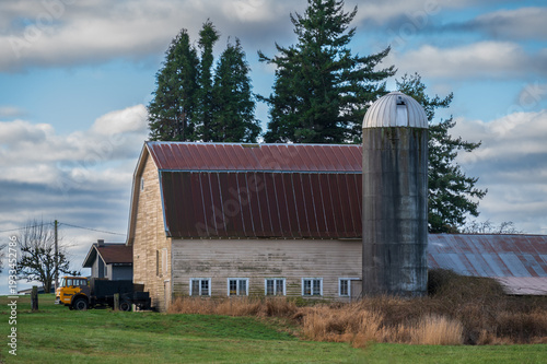 Old wooden barn and silo in a rural area in the Pacific Northwest on a beautiful spring day. Whatcom County in northwest Washington is a hotbed for old abandoned barns among the fertile farmland.