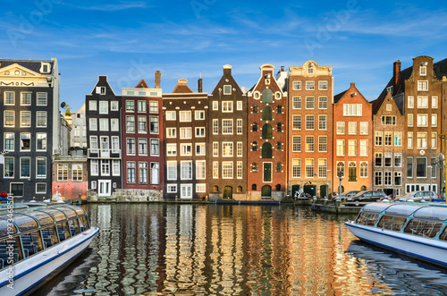 Historic buildings on Damrak canal in Amsterdam, Netherlands on a sunny day