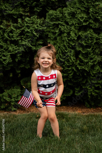 A little girl dressed for the Fourth of July waves an American flag