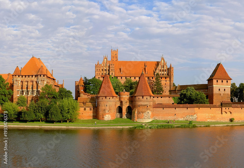 Summer view of the Malbork Castle across the Nogat river. Iconic Polish landmark and historical Teutonic fortress.
