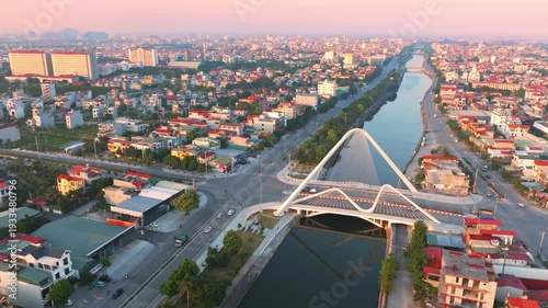 An aerial view of the Cau Bong Lau Bridge in Ninh Binh, Vietnam, showcasing its unique architectural design as cars and motorbikes traverse it at sunrise