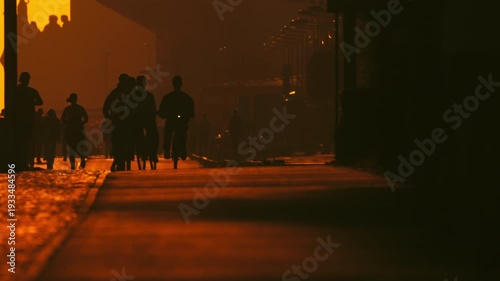 Silhouetted people walking and cycling at sunset