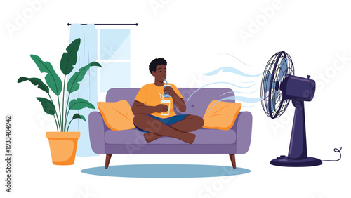 Man relaxes on a purple sofa with a cool drink while a large electric fan blows air, helping him stay cool in the heat.
