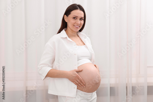 Beautiful pregnant woman touching her belly near curtains at home Free Download Beautiful pregnant woman touching her belly near curtains at home - GFXLoad