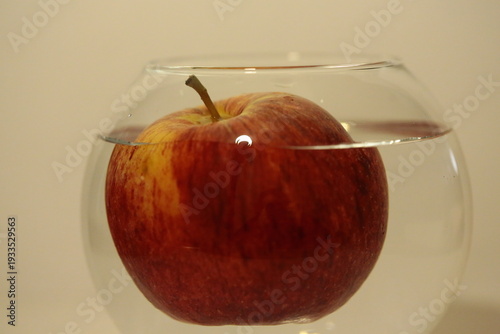 A red apple in a glass bowl full of water.