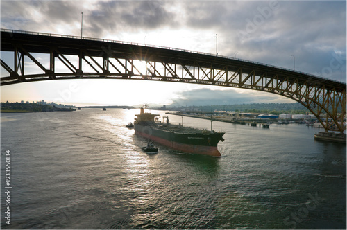 Canada, BC, Vancouver.  Freighter is escorted under the Second Narrows bridge on the Burrard Inlet by harbour tugs.