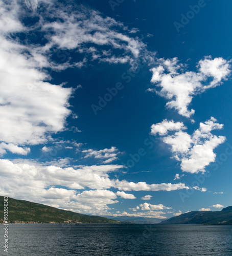 Canada, BC, Vernon.  White clouds and deep blue sky over Okanagan Lake.