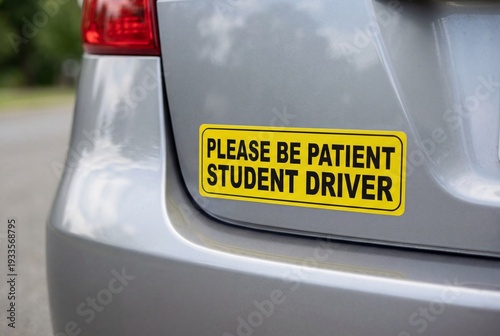 Yellow student driver bumper sticker on rear of silver car