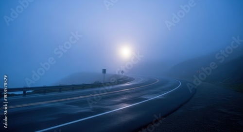 Road disappearing into fog with light source in the distance scenic landscape
