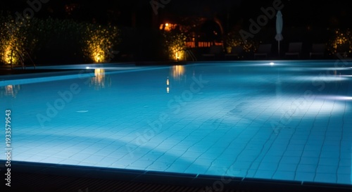 Nighttime illuminated swimming pool with calm water reflections and soft lighting