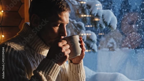 Cozy winter morning: man enjoys hot drink by snowy window in a cabin retreat