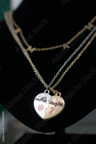 Heart-shaped necklace symbolizing the bond between mother and daughter displayed on a black stand