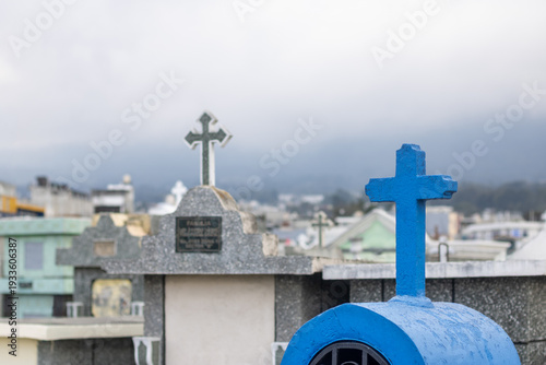 Graves and crosses in a cemetery with cloudy sky and hill in the background in the early morning hours