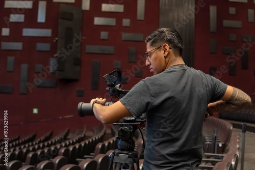 Cameraman filming video production in empty auditorium