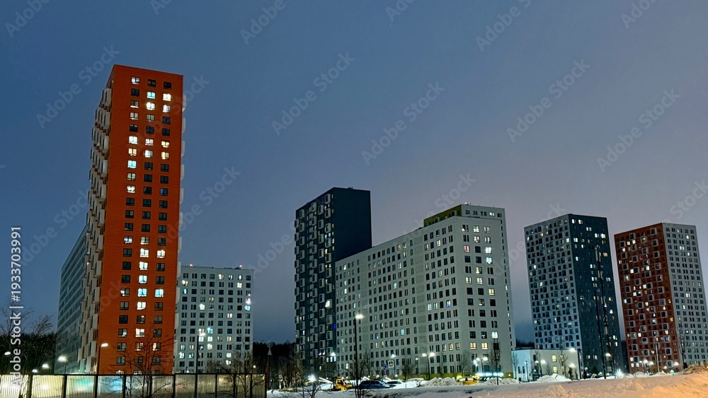 Obraz premium Modern colorful high-rise apartment buildings of Salaryevo Park residential complex in Moscow at dusk. Urban architecture with vibrant orange, green and grey facades under evening sky.