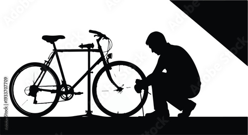 Silhouette of a person fixing a bicycle tire against a stark background.