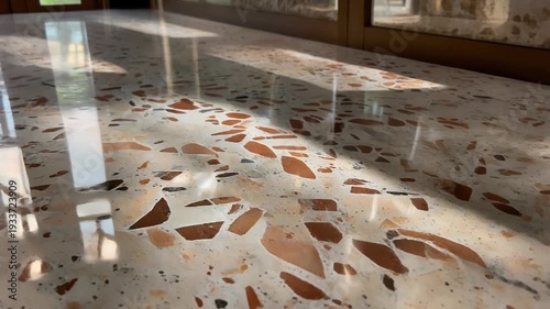 A polished terrazzo floor reflecting sunbeams in a modern interior space with natural light pouring through the windows