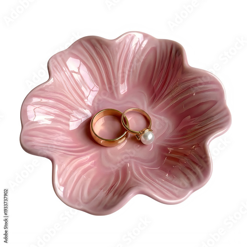 Elegant pink glossy ceramic flower shaped jewelry dish holding two beautiful golden wedding rings on transparent background.