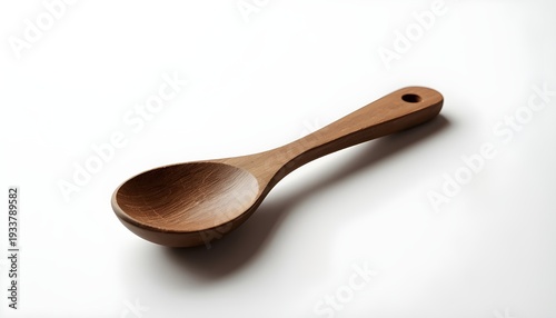 A wooden spoon lies on a plain white surface, casting a subtle shadow.