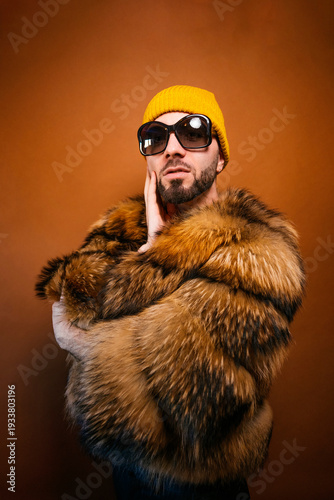 Fashionable man in fur coat and sunglasses posing