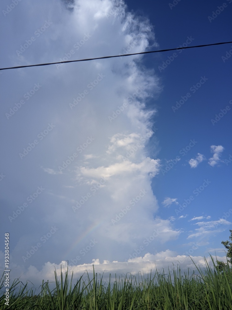 Fototapeta premium Dynamic weather spectacle where a vast, dark storm cloud front dramatically converges with a clear, vibrant blue sky, revealing nature's powerful atmospheric transition