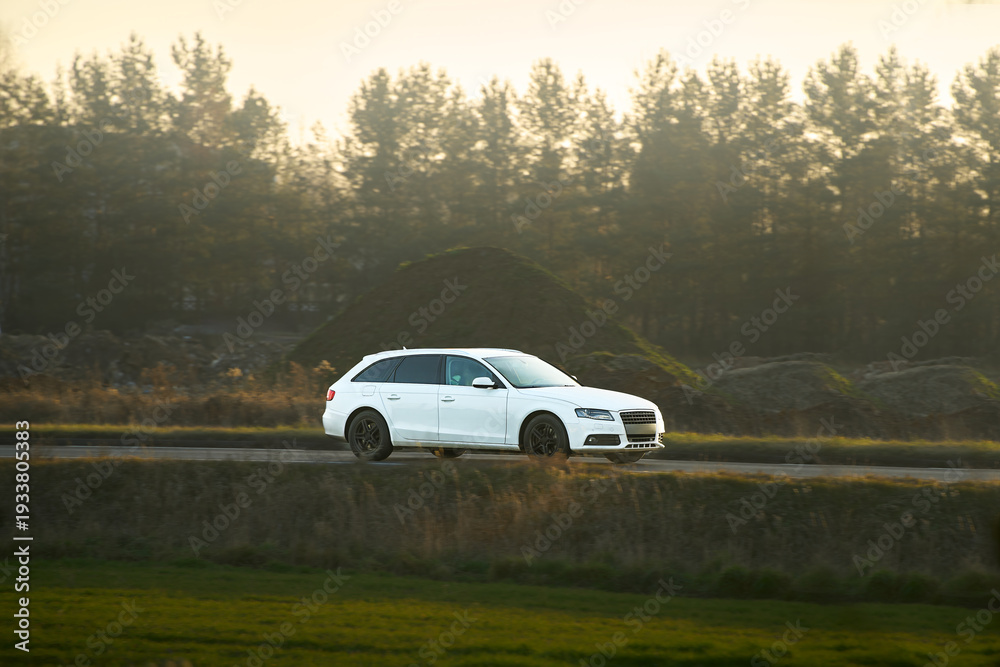 Fototapeta premium White car driving through countryside