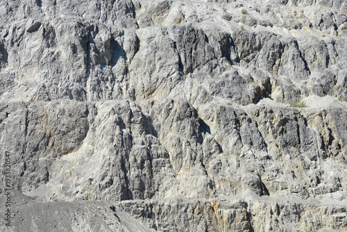A close up view of a steep stone quarry face showing intricate rocky layers and rough textures of excavated limestone under bright daylight