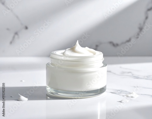 A small glass jar filled with white, creamy skincare product, set against a marble backdrop with light streaks