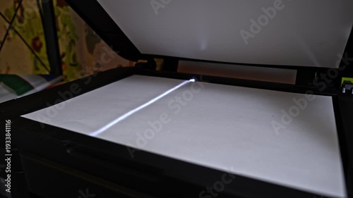 Closeup view of flatbed scanner slowly scanning paper document. Optical device moving light bar during office digitization process.