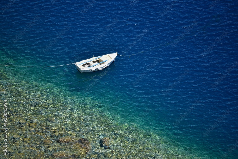 Fototapeta premium Seascape with scenic view of a traditional Greek fishing boat on the waters of Therasia island in Cyclades, South Aegean Greece.