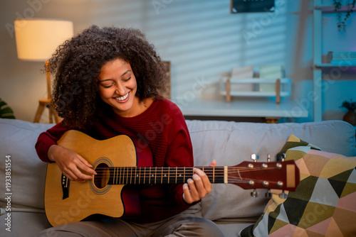 Latina beautiful woman playing guitar in living room at home. 