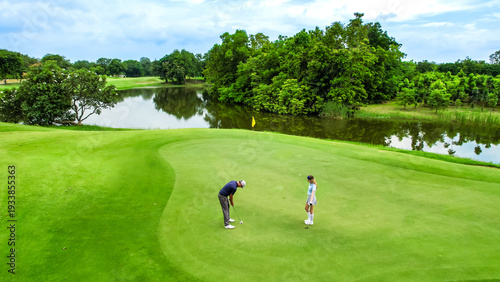 Drone view of young golfers swing clubs together on a scenic golf course.