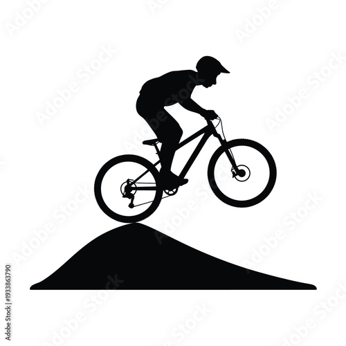 Silhouette of a mountain biker performing a jump on a dirt hill